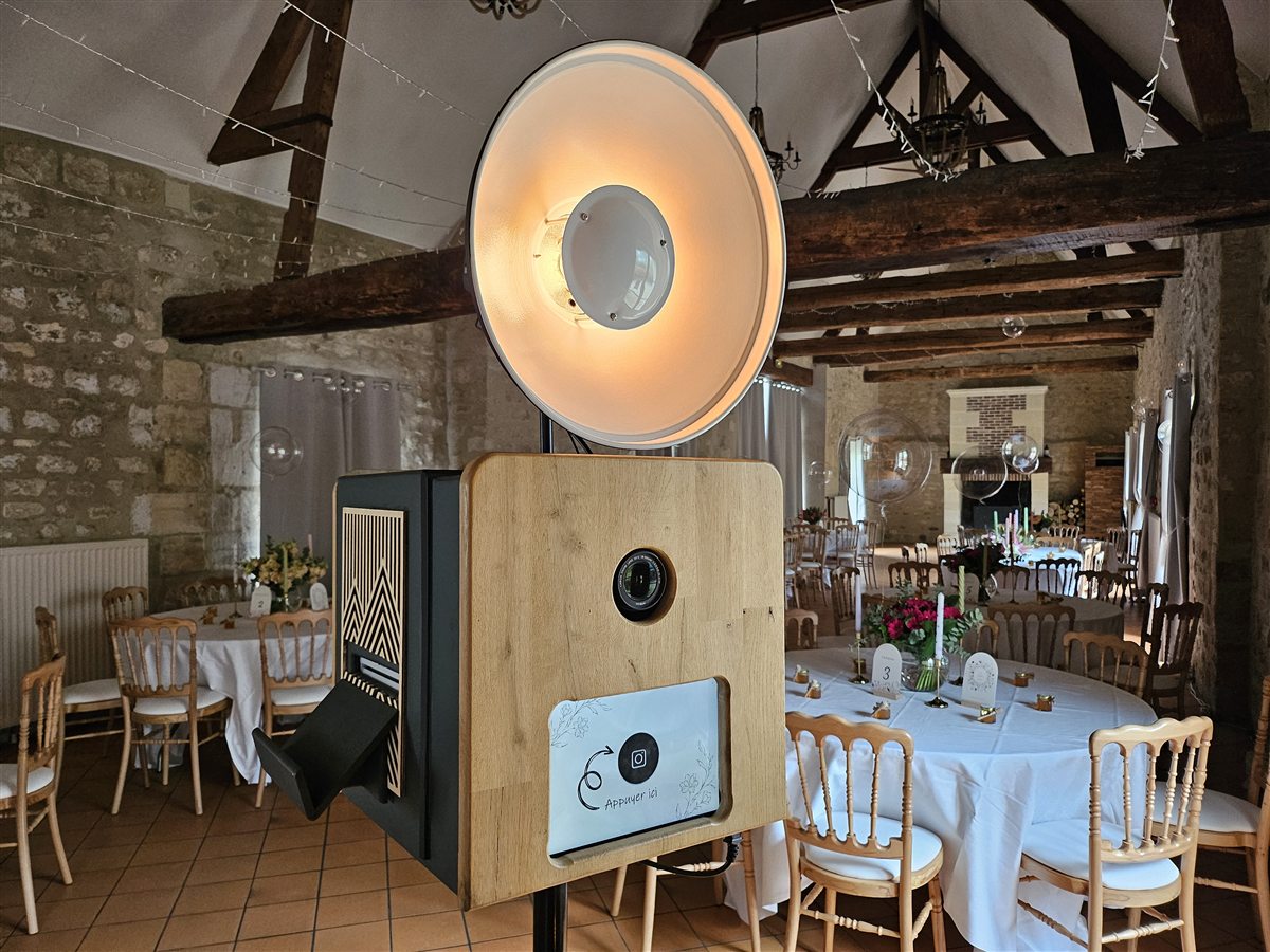 Photobooth WoodBooth installé dans une salle de mariage avec tables dressées